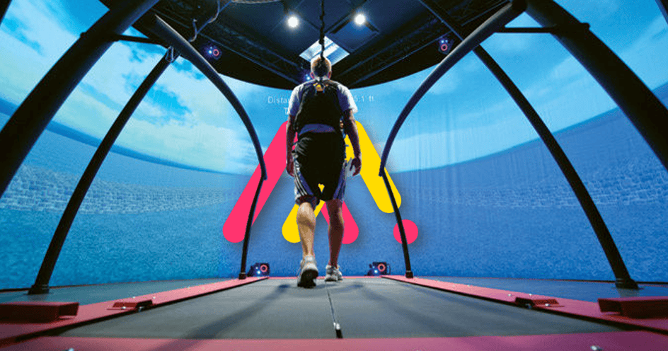 Una persona camina sobre una cinta dentro de un entorno de realidad virtual en forma de cúpula que muestra gráficos digitales en grandes pantallas circundantes.