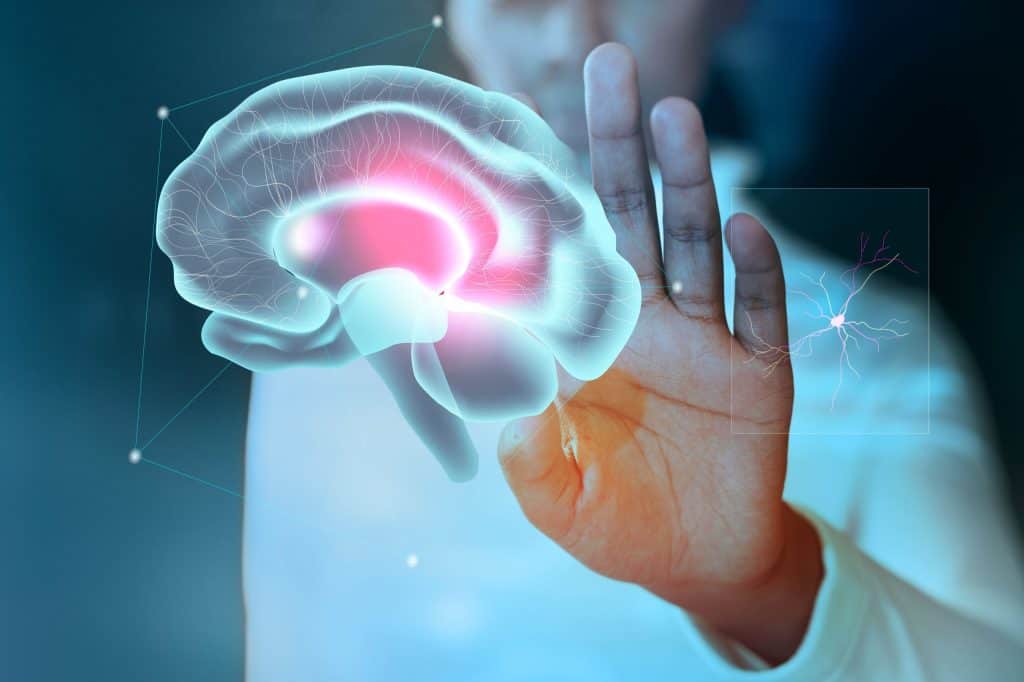 Una persona levanta la mano delante de un holograma digital de un cerebro humano, que destaca la actividad y las conexiones neuronales.